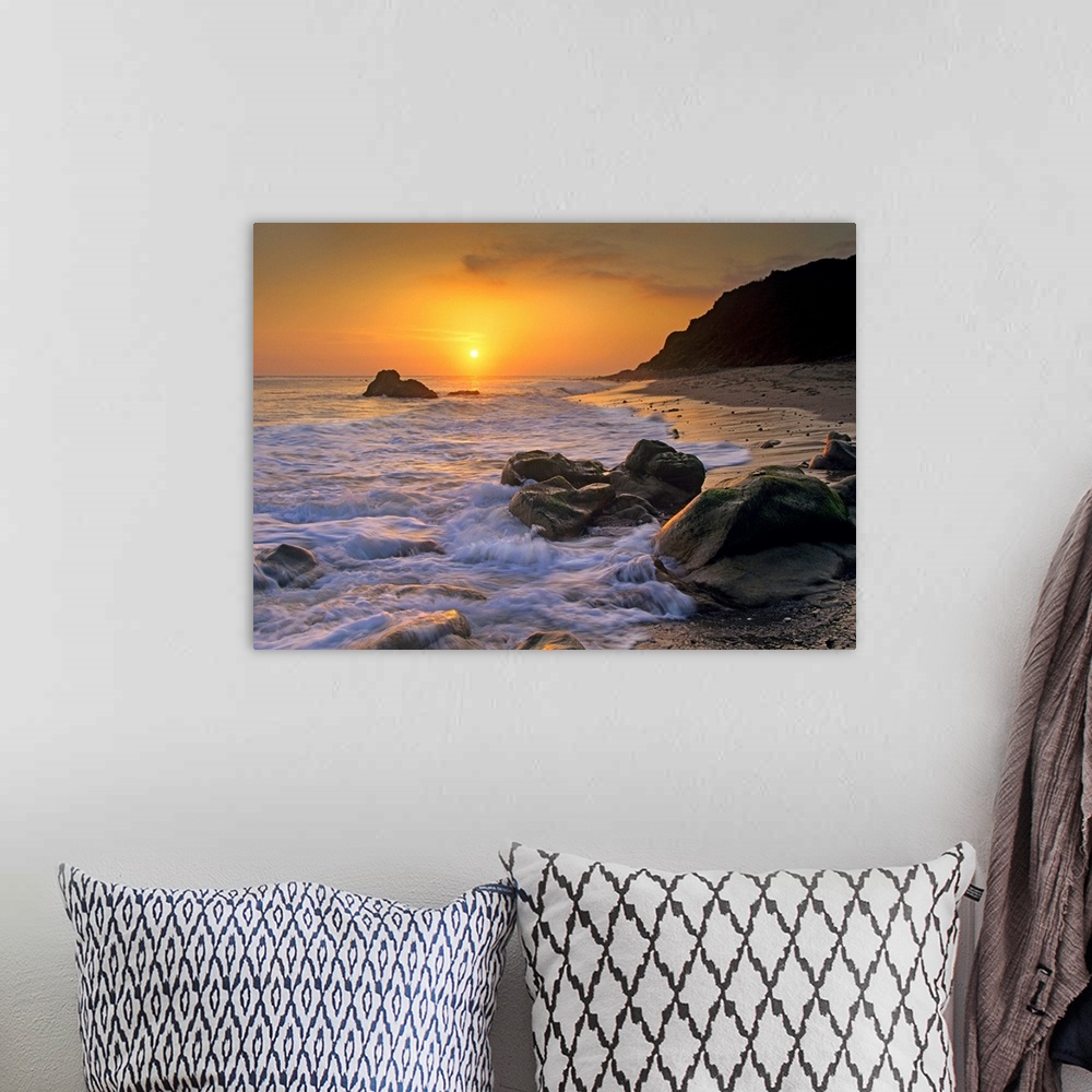 A bohemian room featuring Large landscape photograph of a golden sunset over the rocky shoreline at Leo Carrillo State Beac...