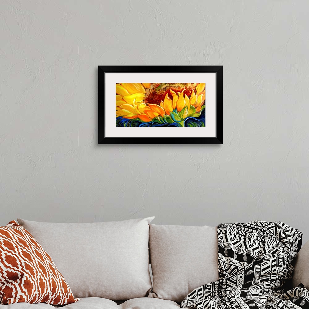 A bohemian room featuring Wide painting of a sunflower close up with an abstract blue, black, and green background.
