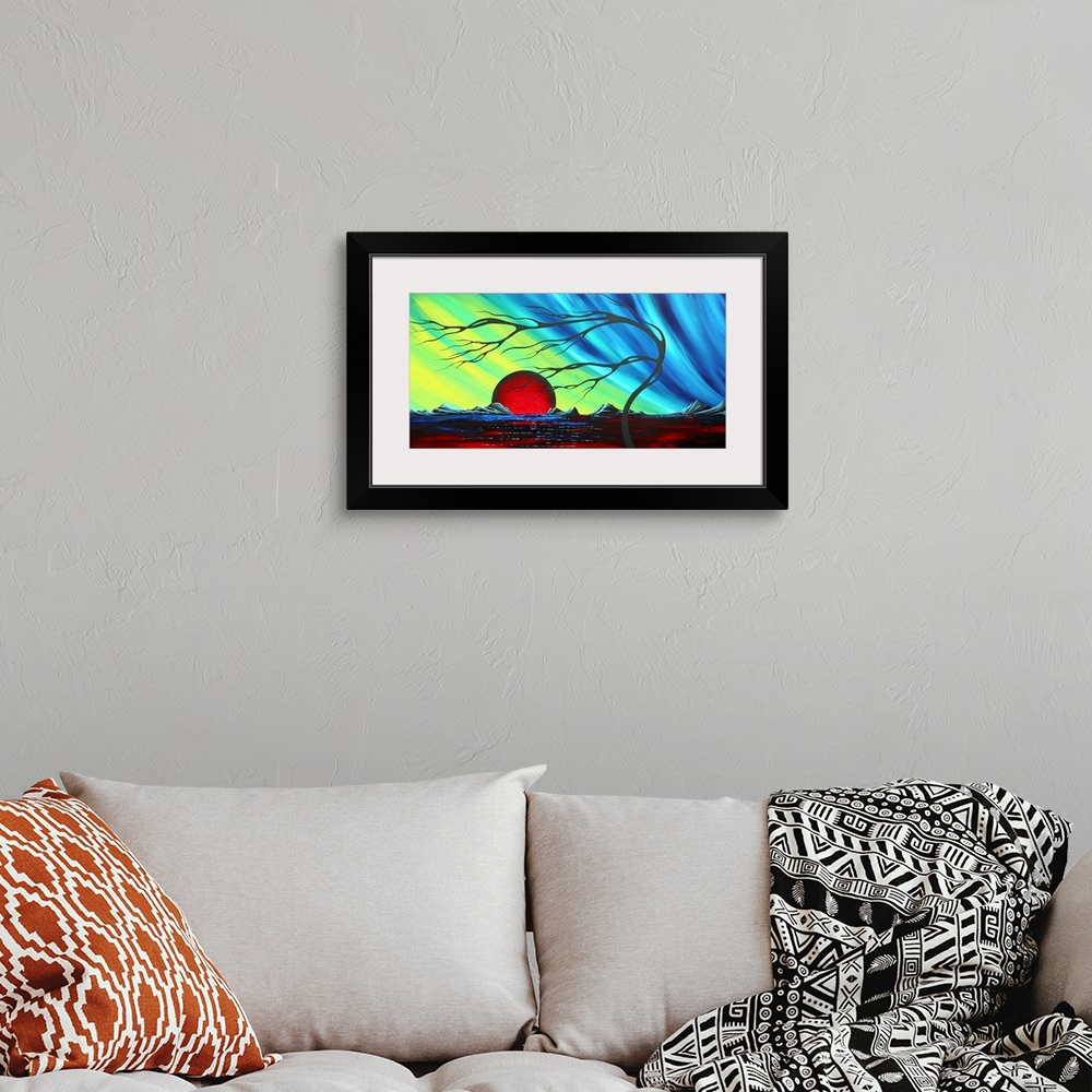 A bohemian room featuring Abstract artwork of a deep red sun that sits on the horizon with a cool colored sky above it. A f...