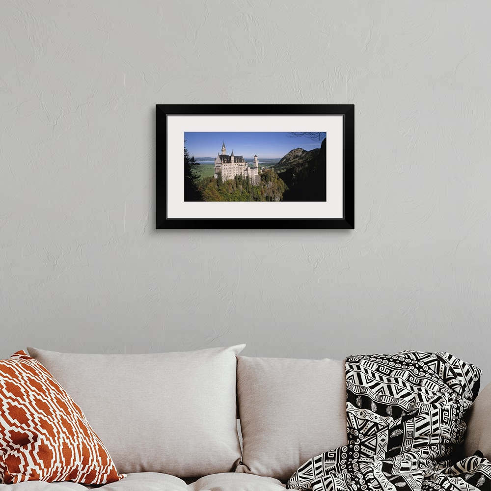 A bohemian room featuring A landscape photograph of an elegant caste build on top of a steep, tree covered hill.