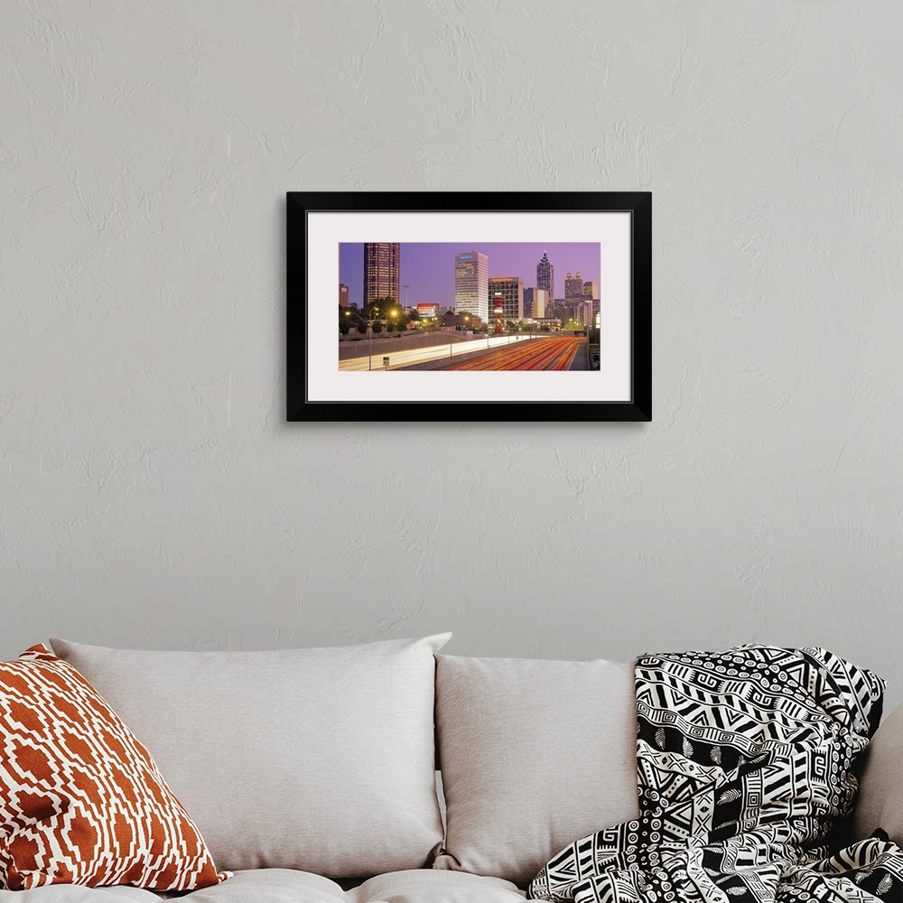 A bohemian room featuring Panoramic photograph of highway filled with light trails lined by lit up buildings at sunset.
