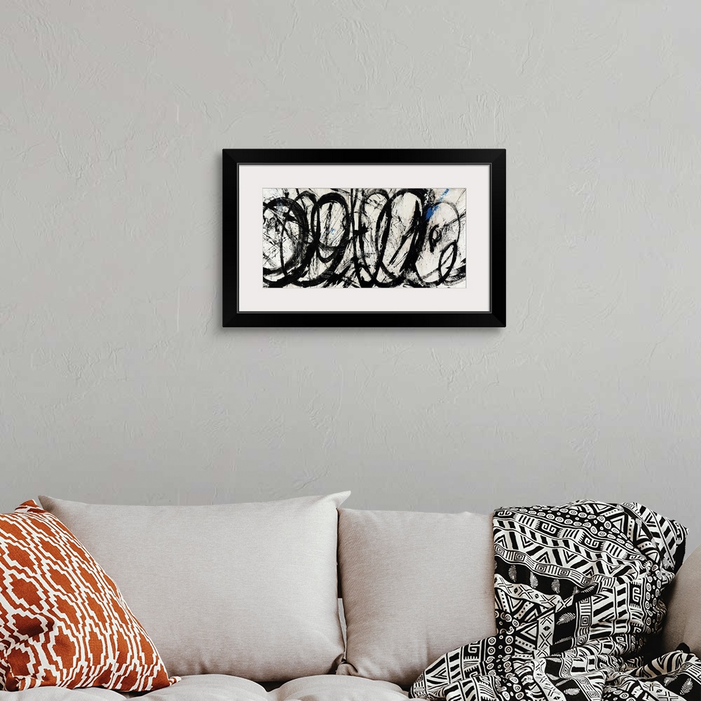 A bohemian room featuring An abstract piece of artwork that has swirls of black paint throughout the panoramic print.