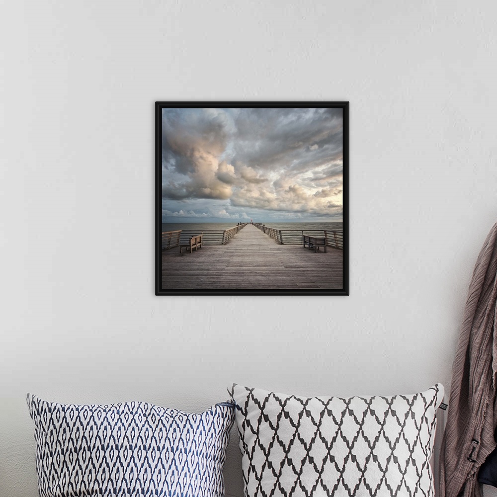 A bohemian room featuring A wooden pier leading to the ocean with dramatic clouds above.