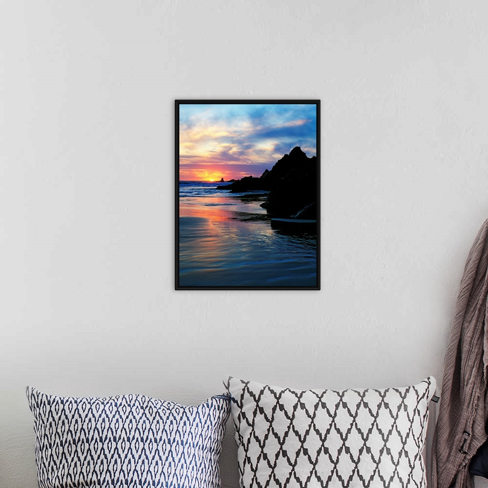 A bohemian room featuring Sun below the horizon in a seascape with a rocky beach and waves.