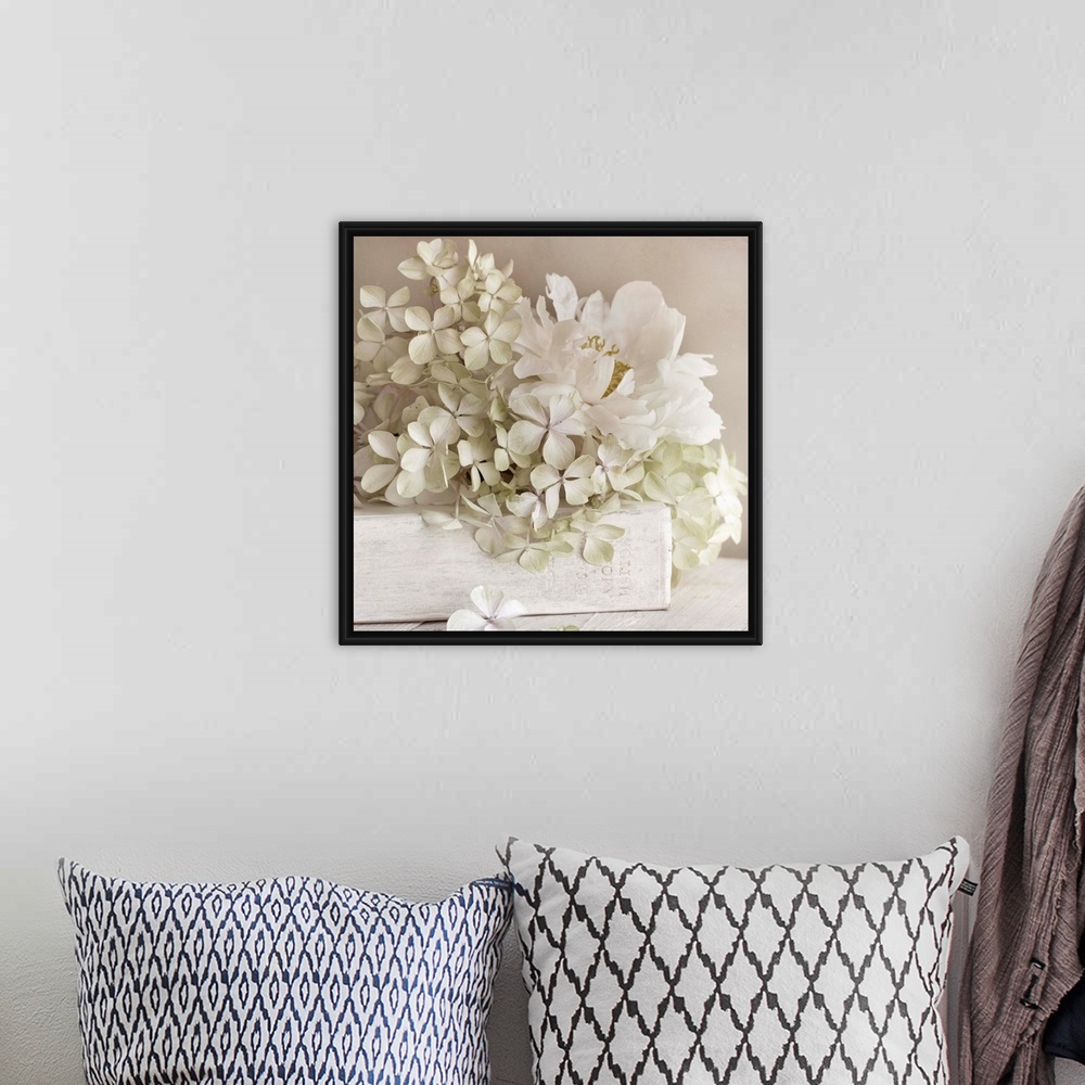 A bohemian room featuring Square photo on canvas of white flowers laying on top of a white book with the spine facing the c...