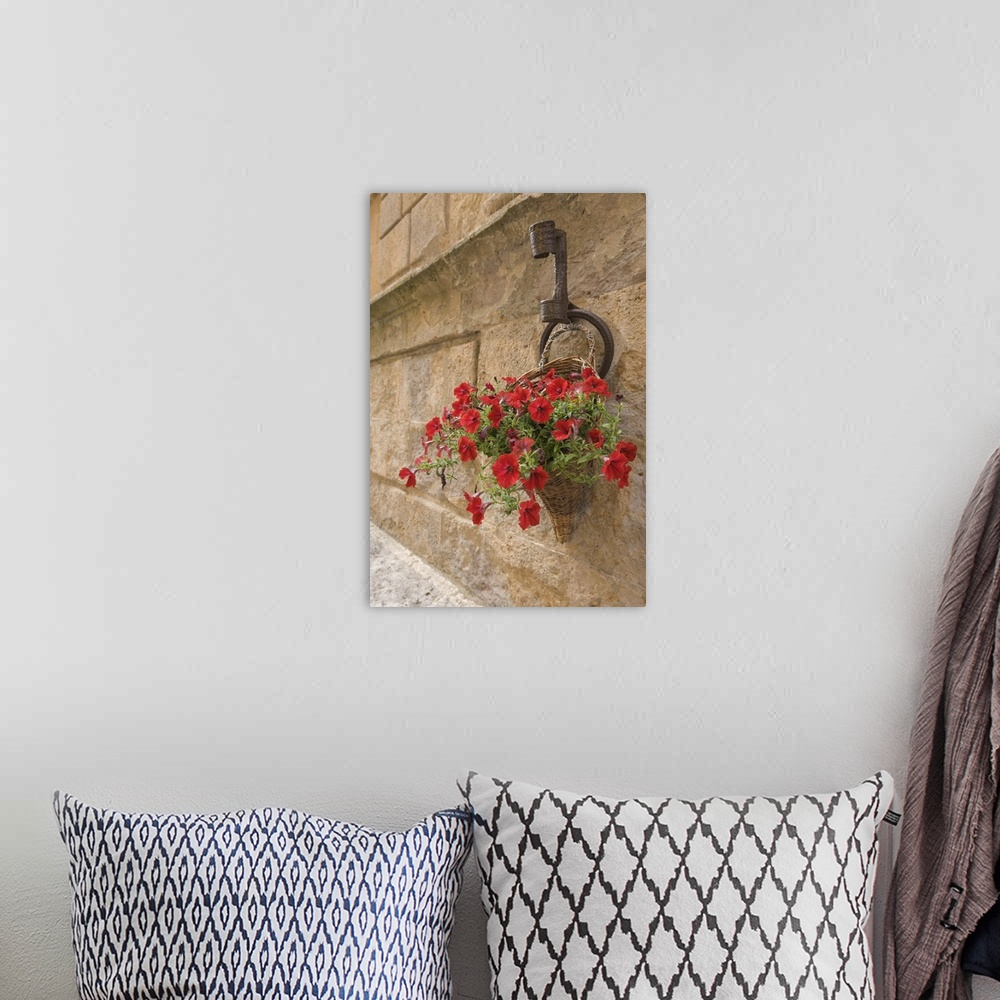 A bohemian room featuring Italy, Tuscany, Pienza. Colorful petunias spill from a basket on a stone wall.