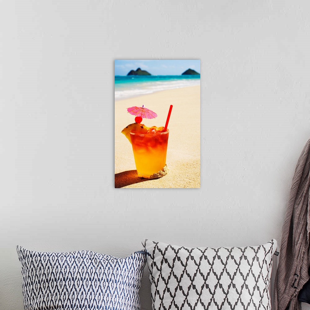 A bohemian room featuring A mai tai garnished with pinapple and a cherry, sitting in the sand on the beach.