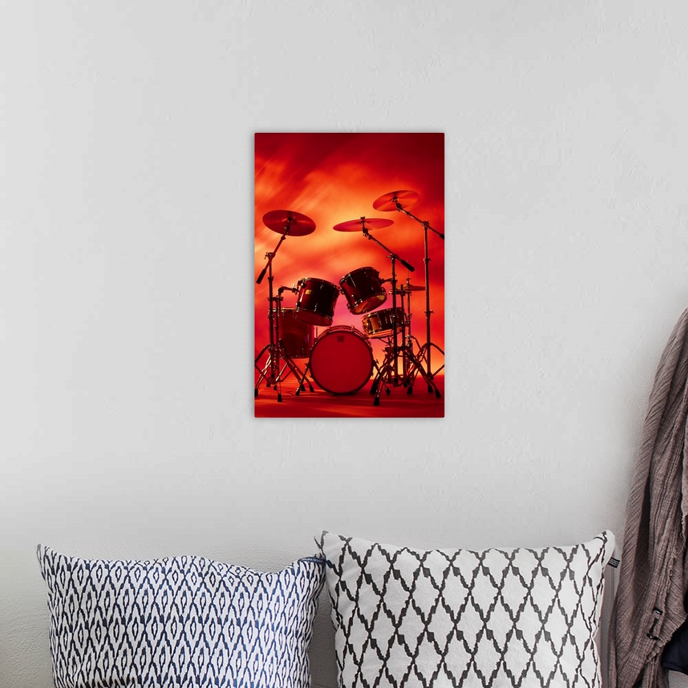 A bohemian room featuring Large vertical photograph of a drum set with symbols, surrounded by warm, fiery lighting.