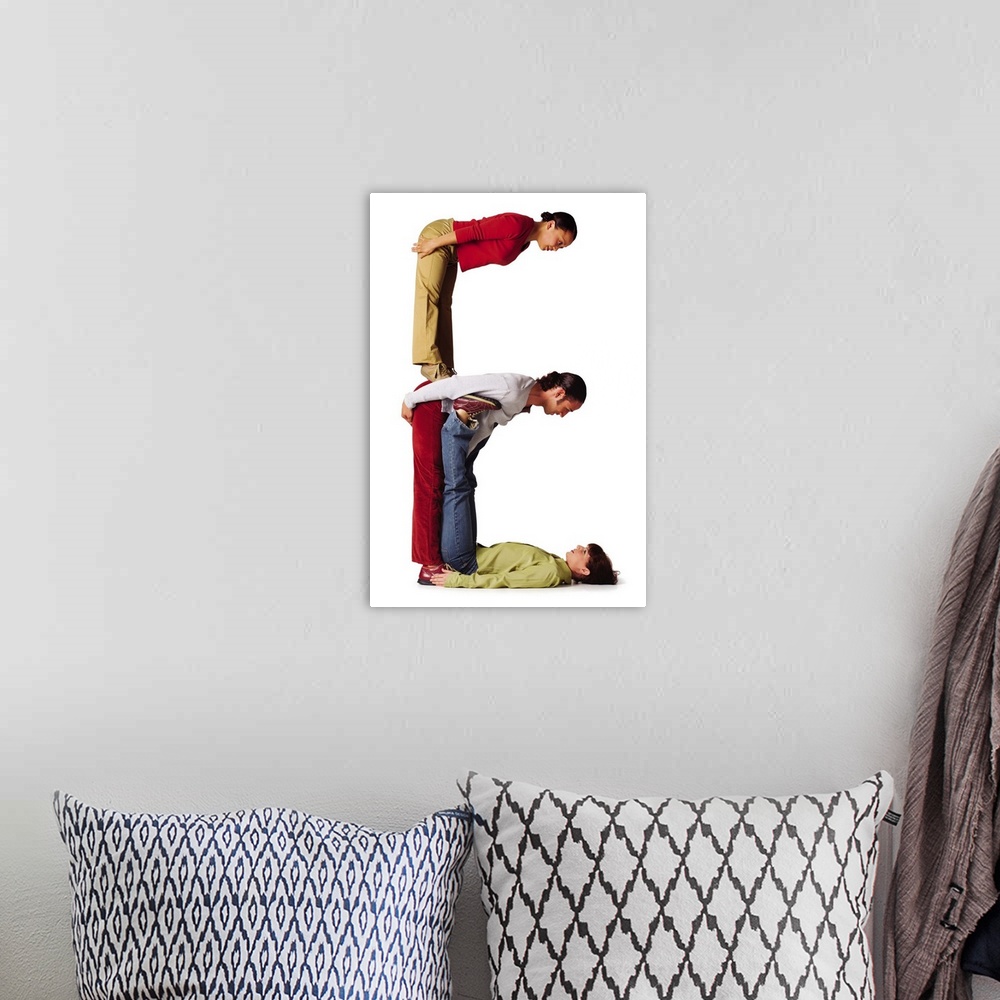 A bohemian room featuring three young adults in colorful clothes create the letter E