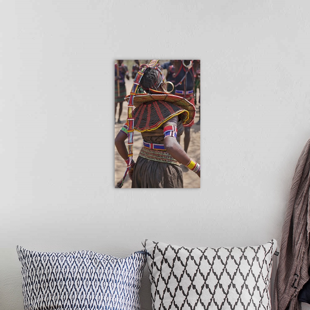 A bohemian room featuring A Pokot woman in traditional attire dances to celebrate an Atelo ceremony. Her broad belt is made...