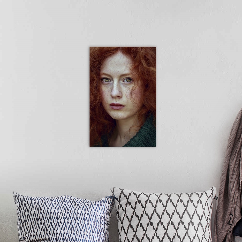 A bohemian room featuring Close-up portrait of female youth with red curly hair and piercing green eyes.