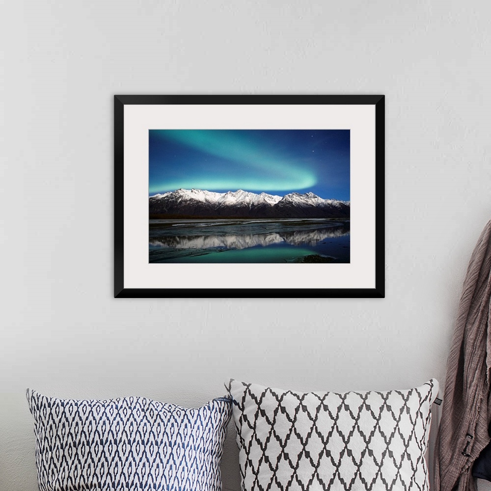A bohemian room featuring A landscape photograph of the aurora borealis and mountains reflecting in a lake filled with ice.