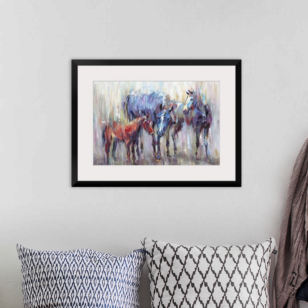 A bohemian room featuring Home decor artwork of two adult multi-colored horses with a small brown one.