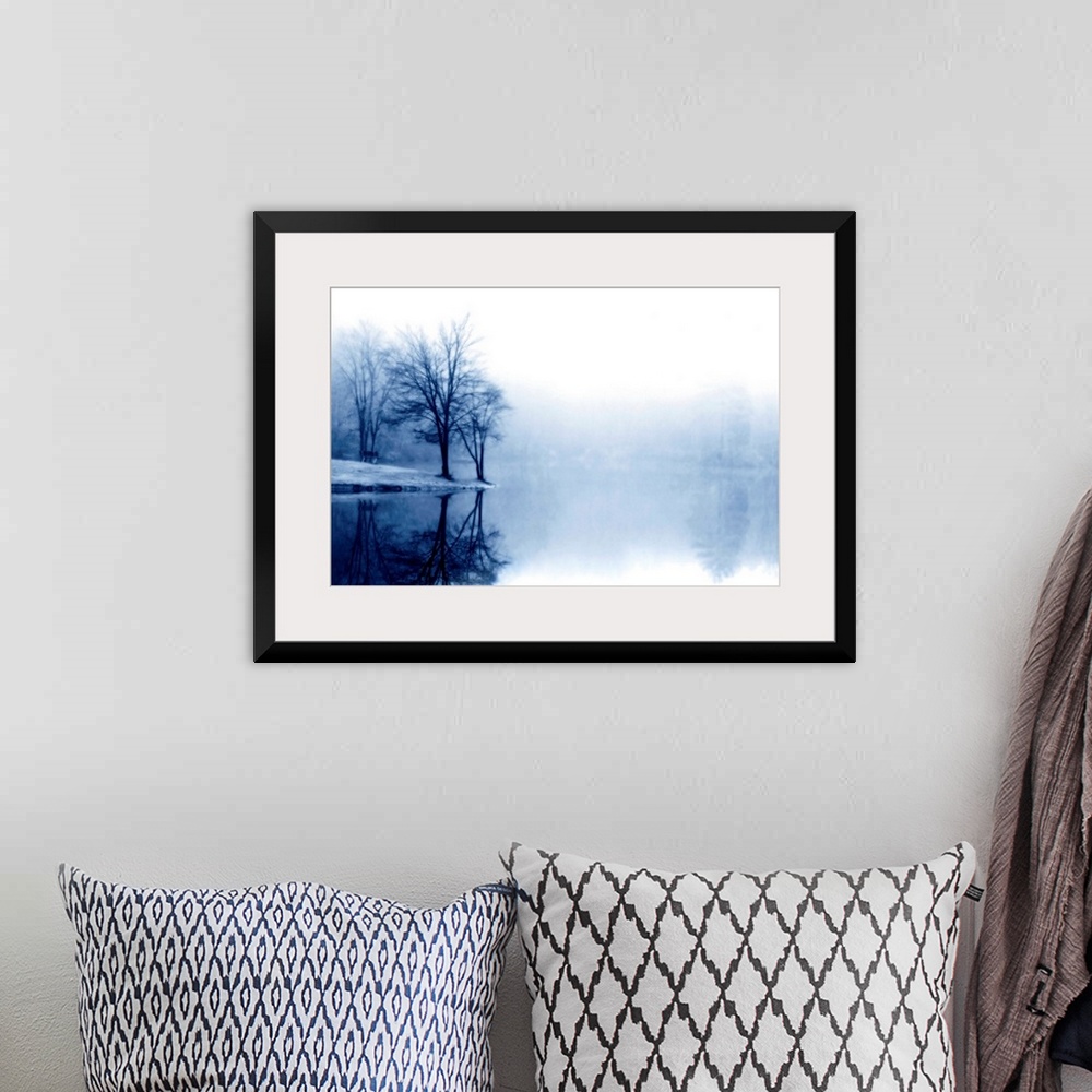 A bohemian room featuring A photograph taken of a lake with bare trees off to the left side and more trees behind dense fog...