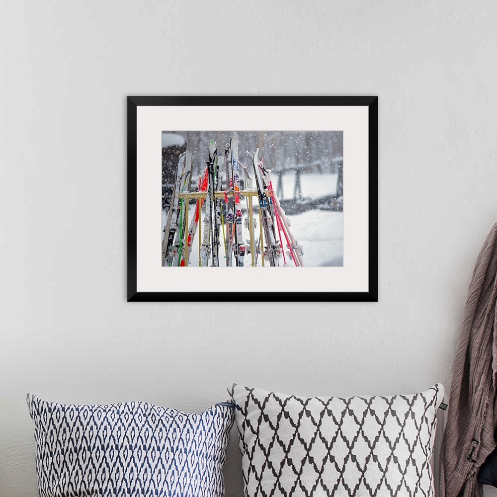 A bohemian room featuring In this photograph multiple skis are stored on an outside rack as large white snowflakes fall all...