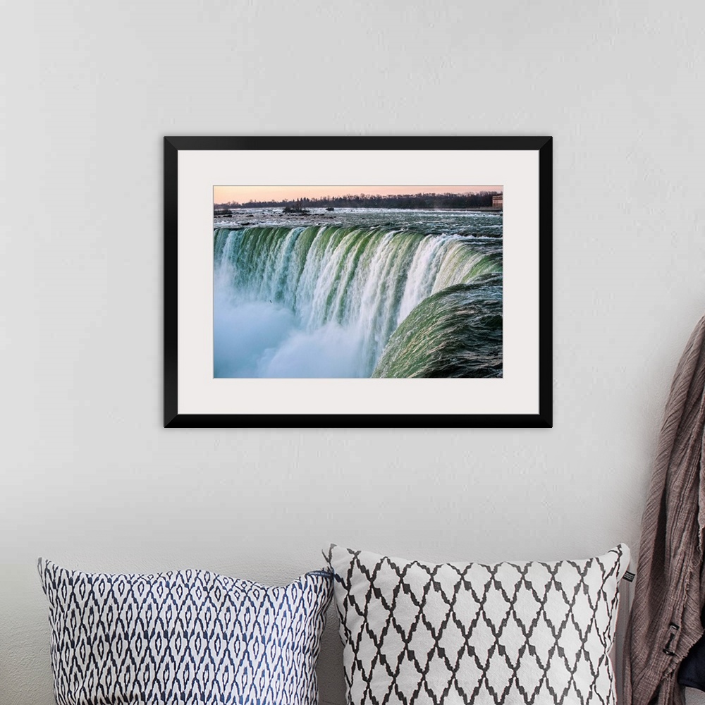 A bohemian room featuring Water cascades down at Horseshoe Falls while dramatic mist ascents to meet the rising sun.