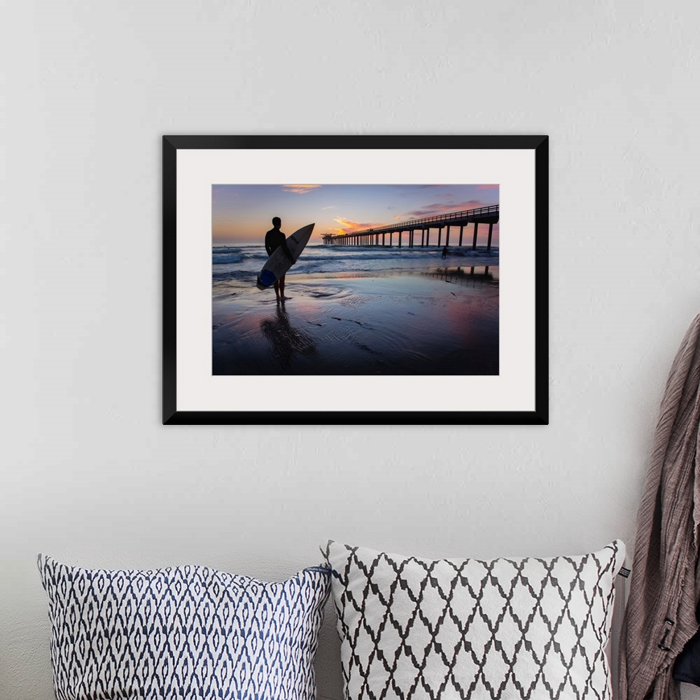 A bohemian room featuring Silhouetted photograph of a man holding a surf board on the shore of Ocean Beach in San Diego, Ca...