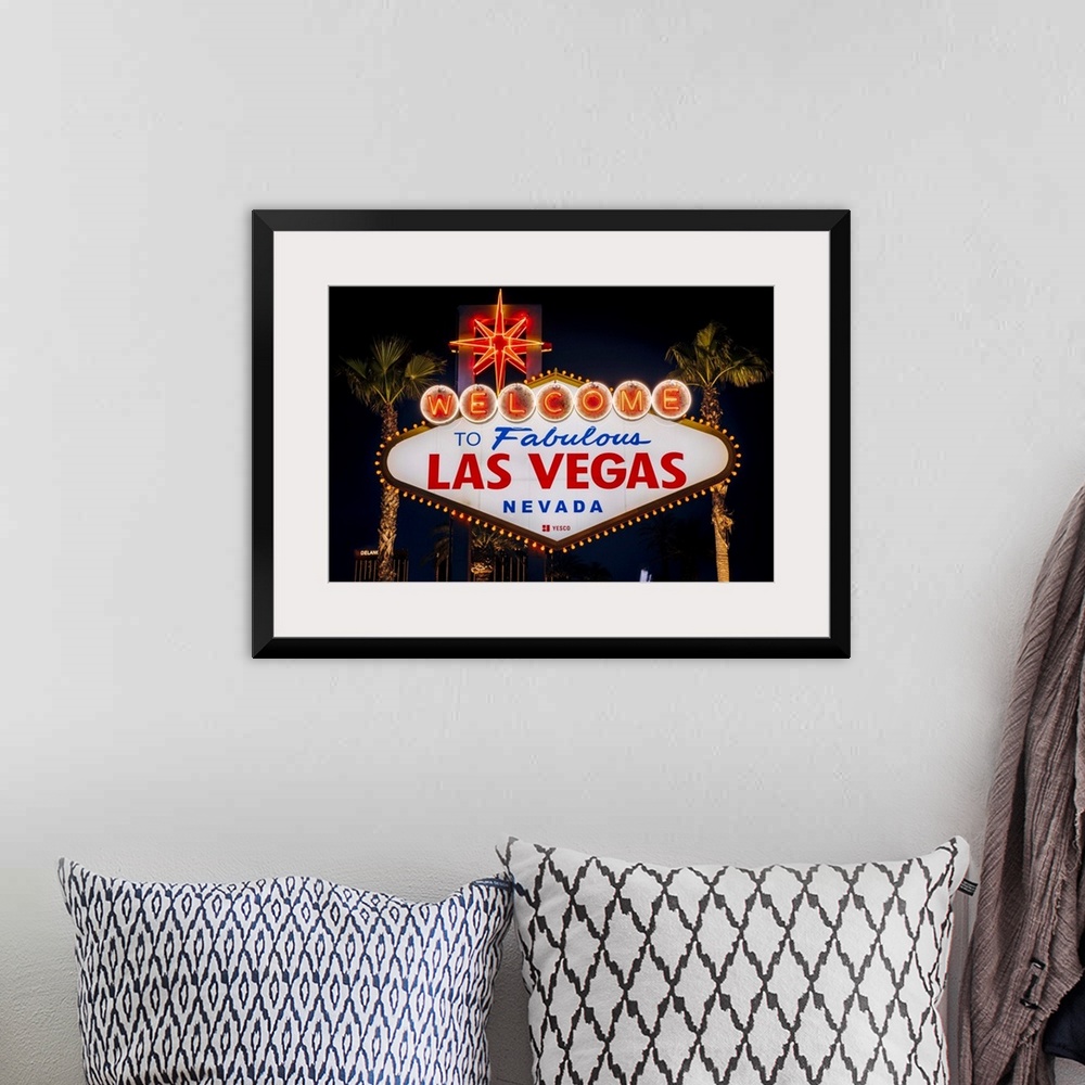 A bohemian room featuring The famous "Welcome to Las Vegas, Nevada" sign is lit at night.