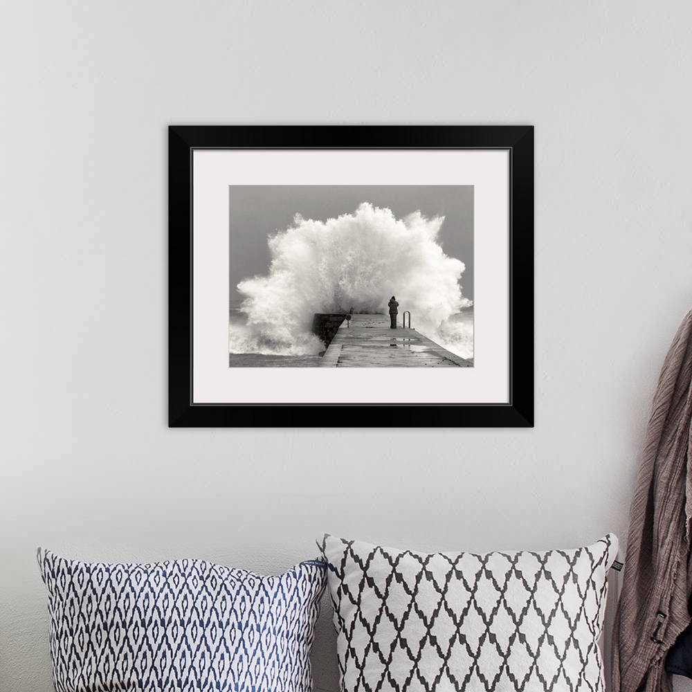 A bohemian room featuring A photographer standing on a pier with waves crashing.