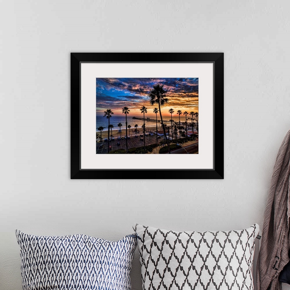 A bohemian room featuring A single image aerial sunset capture of tall palms silhouetted against colorful clouds near Ocean...