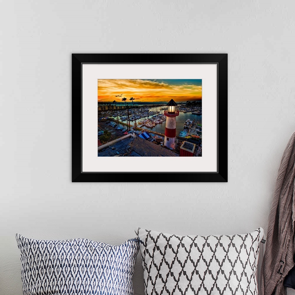 A bohemian room featuring Pelicans glide over the Oceanside Harbor and the little lighthouse glows. Colorful sunset in Ocea...