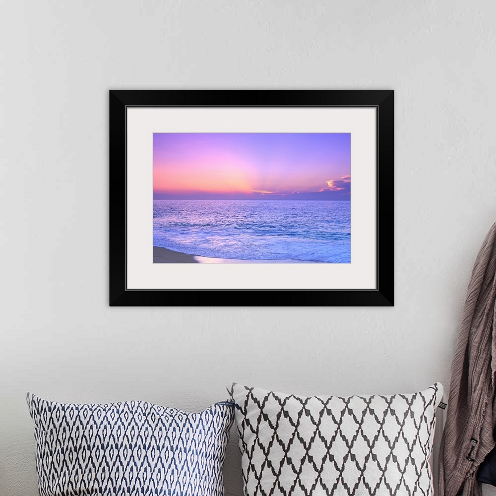 A bohemian room featuring A breathtaking photograph of a sunset over the vast ocean giving the overall picture a soft color...