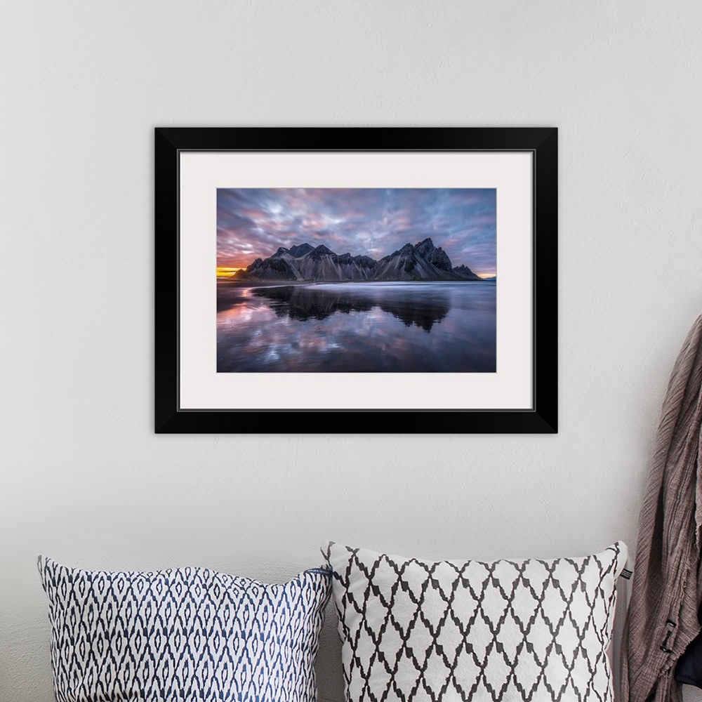 A bohemian room featuring Rugged mountain peaks and a colourful sunset reflected in tranquil water. Iceland.