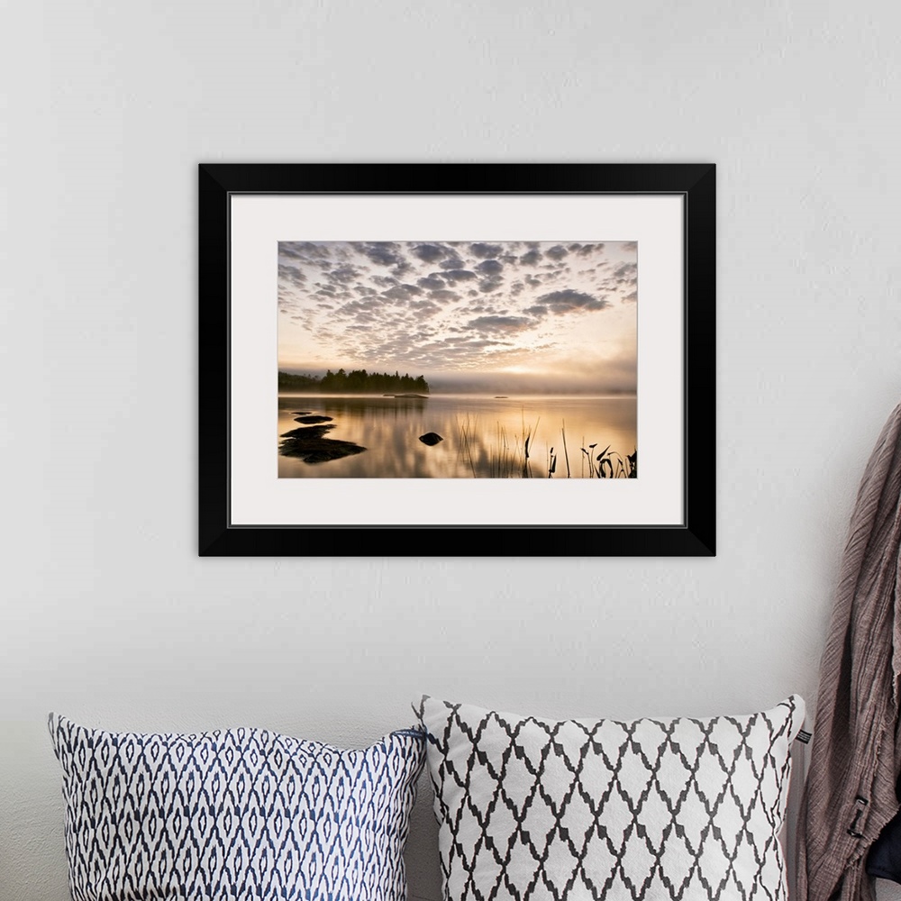 A bohemian room featuring Horizontal photograph on a big wall hanging of the sun set reflecting in a large body of water, a...