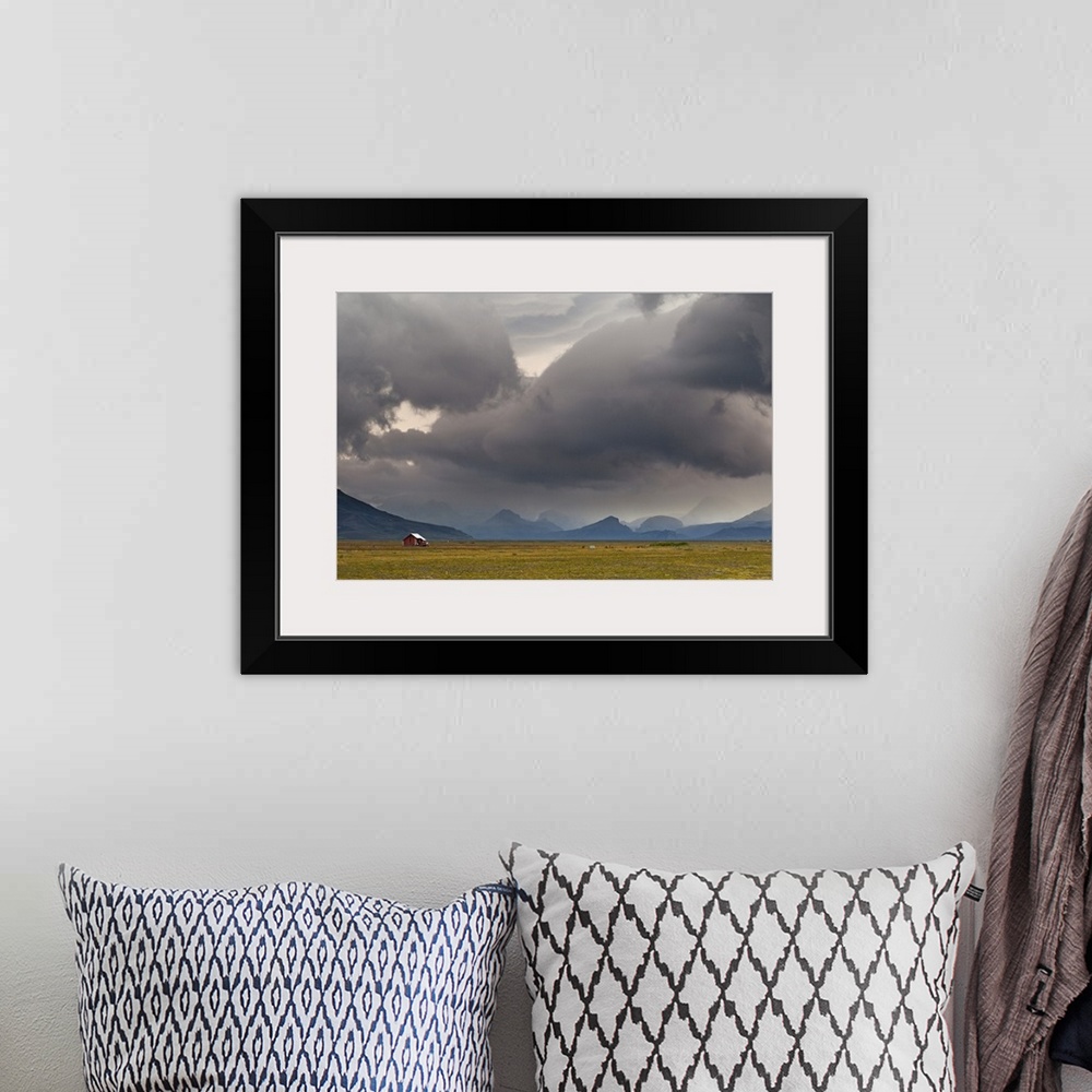 A bohemian room featuring A photograph of a dramatic cloudscape hanging over an Icelandic landscape.