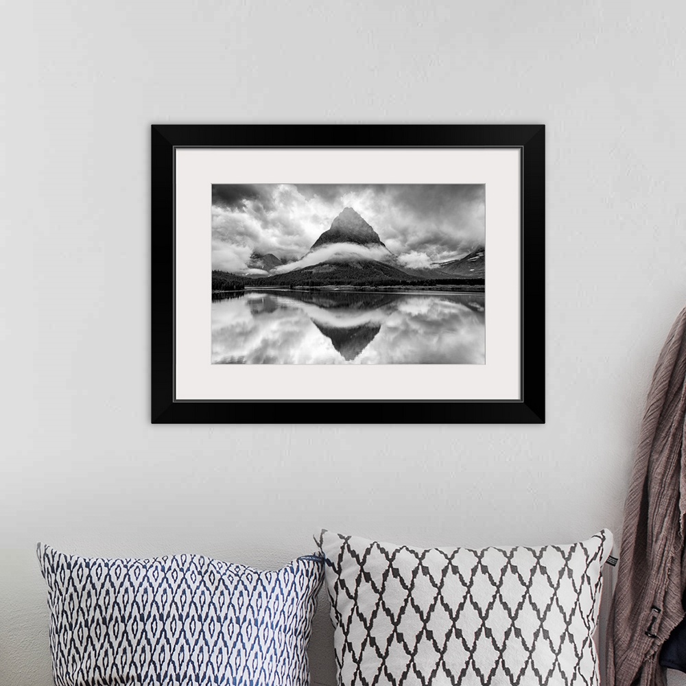 A bohemian room featuring A black and white photograph of a pointed mountain surrounded by a ribbon of cloud while casting ...