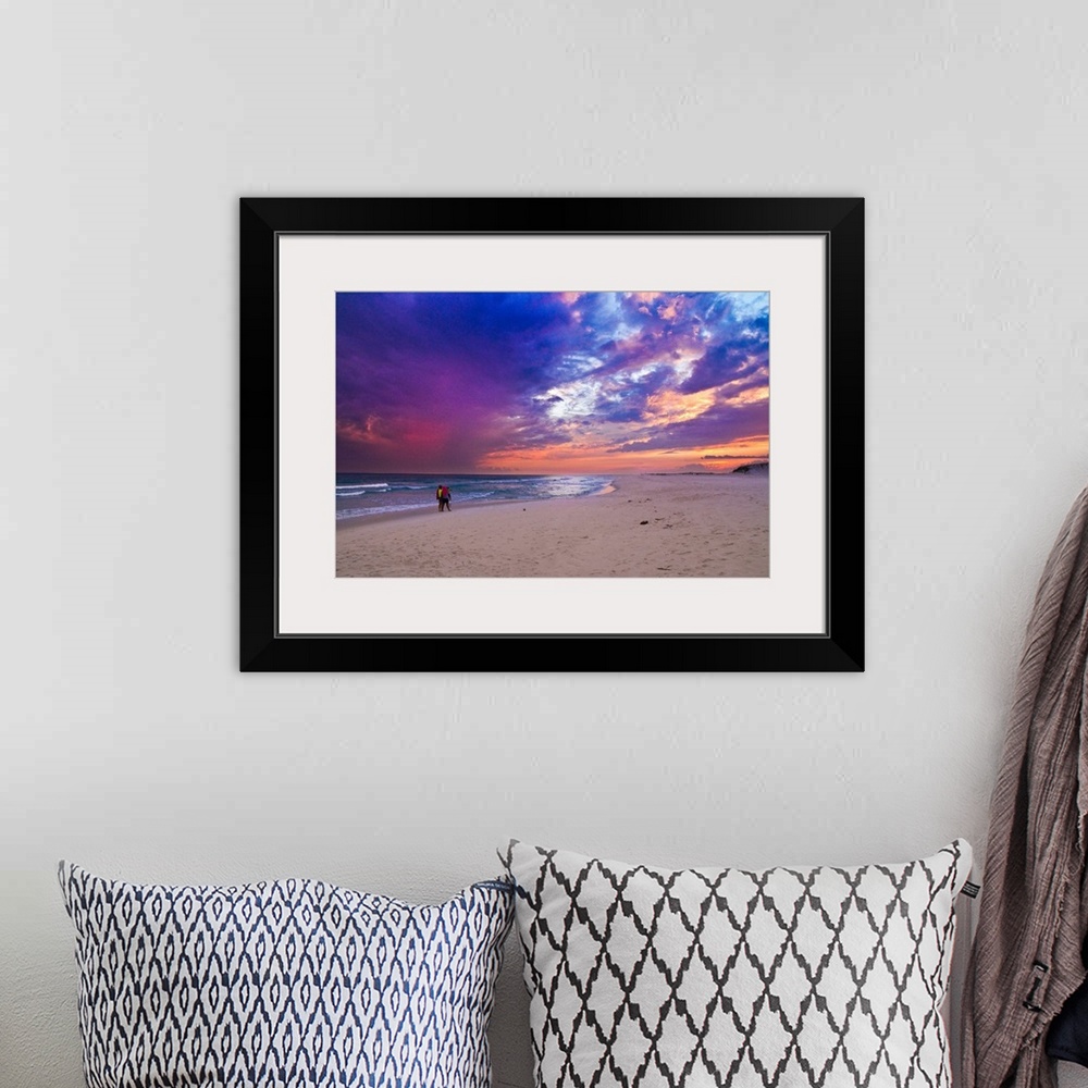 A bohemian room featuring People walking on the beach during a pink and purple sunset along the Gulf Islands National Seash...