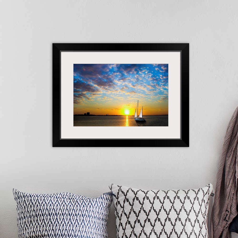 A bohemian room featuring A sailboat sailing into the sun under a blue sky.