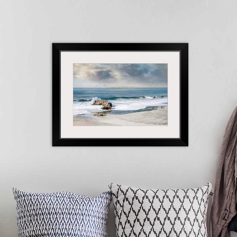 A bohemian room featuring Landscape photograph of waves crashing onto a rock on the sandy shore.