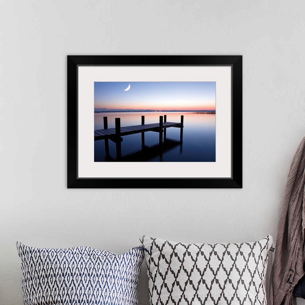 A bohemian room featuring Sunset photograph of a dock over calm water and a half moon in the sky.