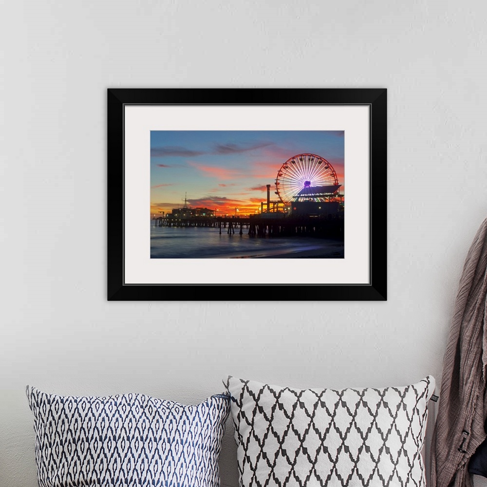 A bohemian room featuring Large artwork of a beach pier during sunset skies with the rides lit up and ocean waves calmly cr...
