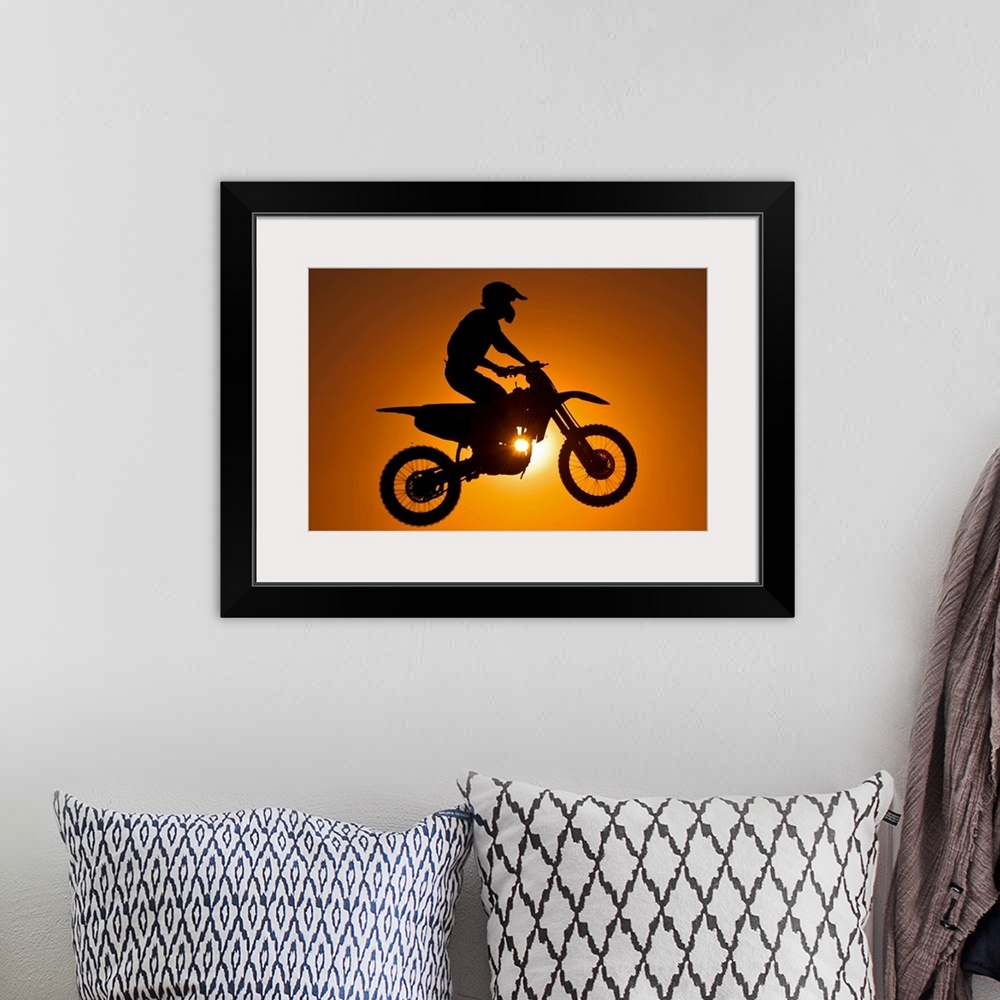 A bohemian room featuring Silhouette of motocross race in mid air at sunset.