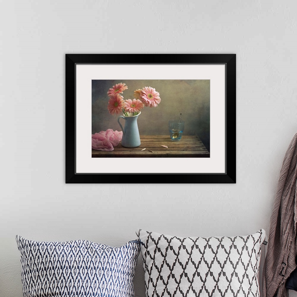 A bohemian room featuring Still life with pink gerberas flowers in blue pitcher jug anf glass of water.