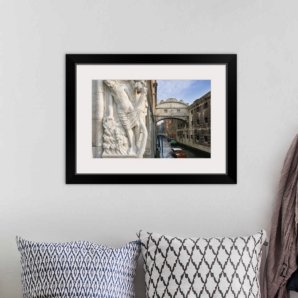A bohemian room featuring Large photograph taken of a bridge in Italy with a boat floating under it and a statue of a man i...