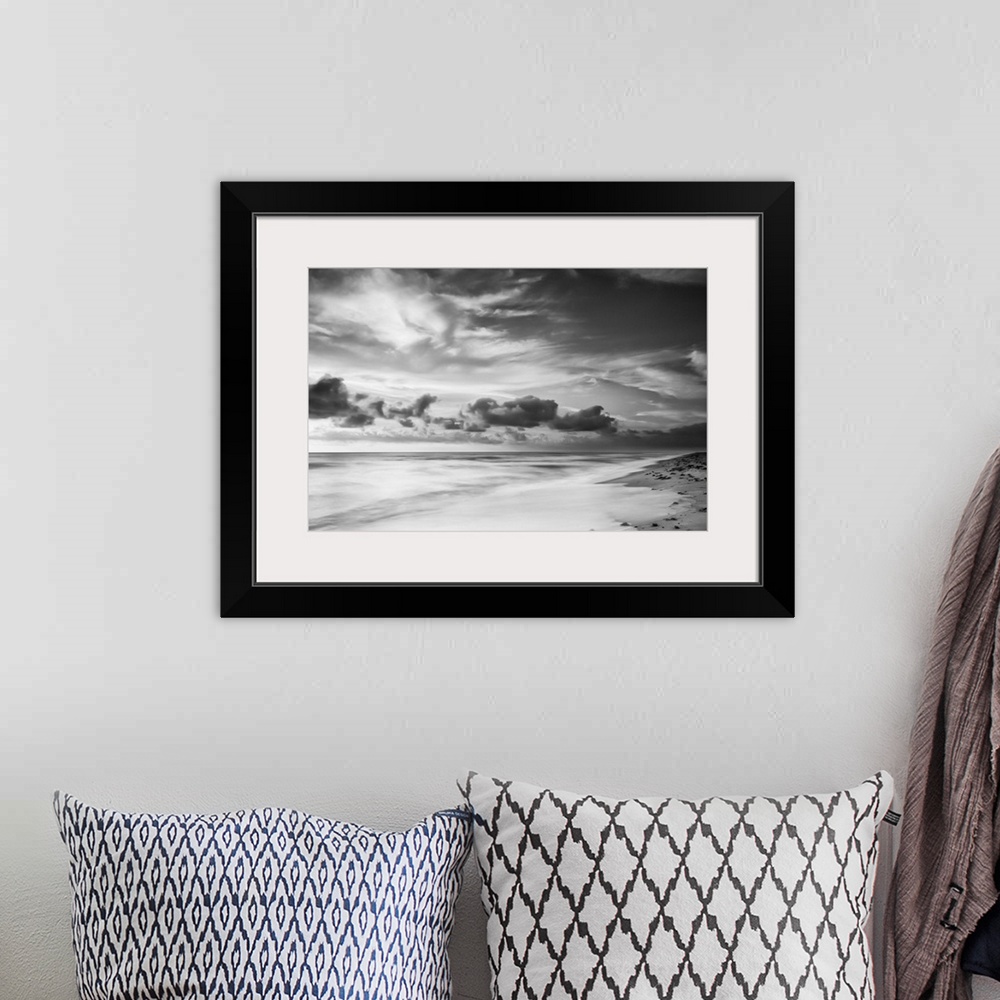 A bohemian room featuring A black and white photograph of a sunrise sky with clouds obscuring the view.