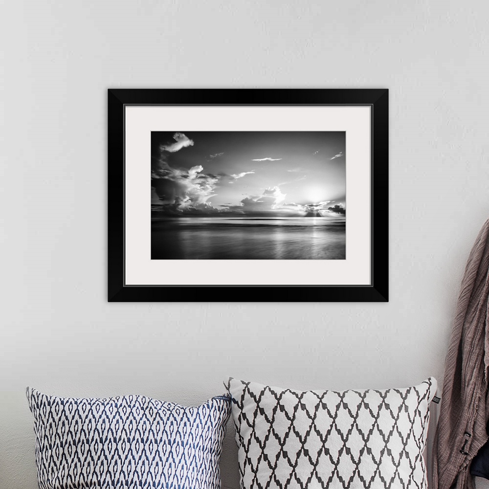 A bohemian room featuring A black and white photograph of a sunrise sky with clouds obscuring the view.