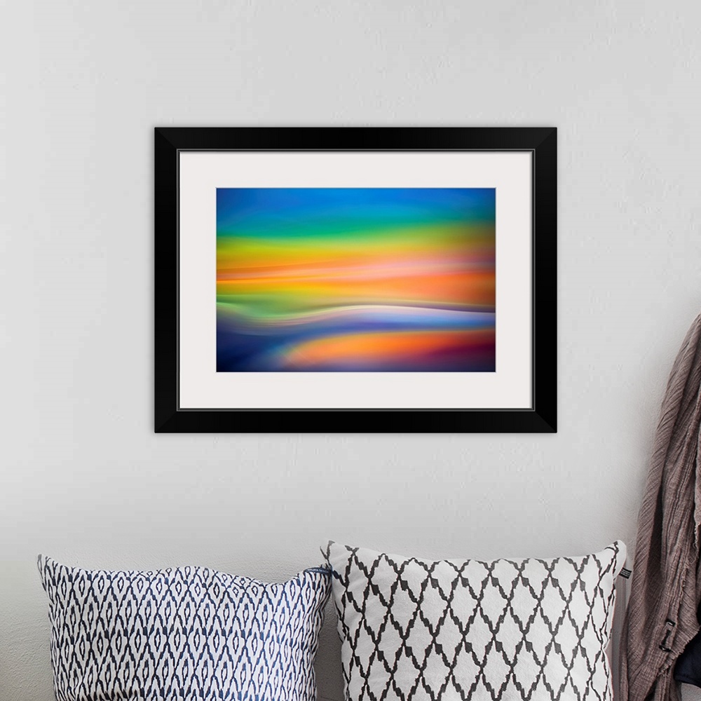 A bohemian room featuring Abstract art with colorful soft focused waves of color running horizontally across the canvas in ...