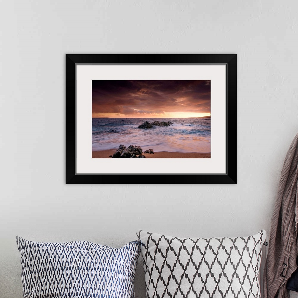 A bohemian room featuring A photograph of a rocky sunset coastal landscape.