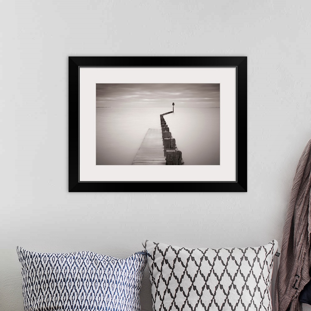 A bohemian room featuring Photograph of dock stretching into ocean under a cloudy sky.
