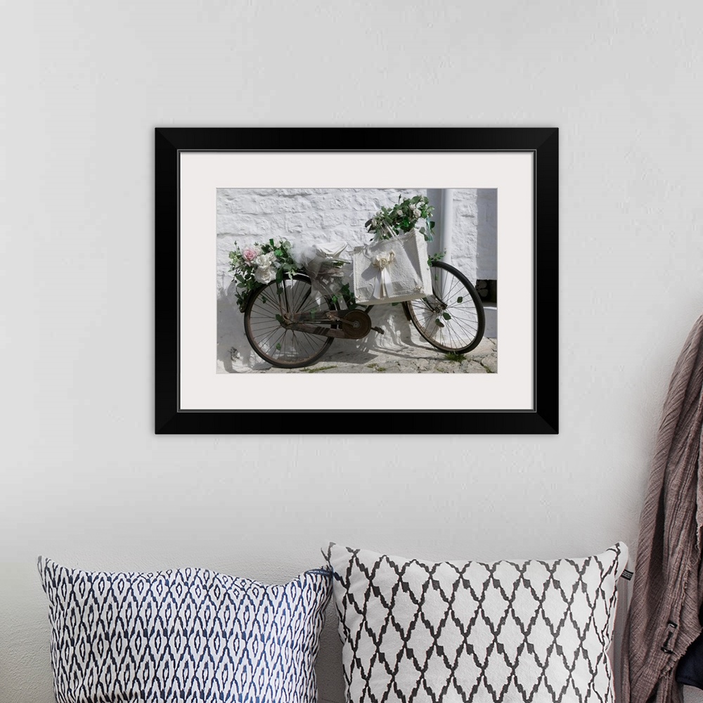 A bohemian room featuring A bike with rusty gears covered in beautiful roses with a decorative ribboned tote bag leaning ag...