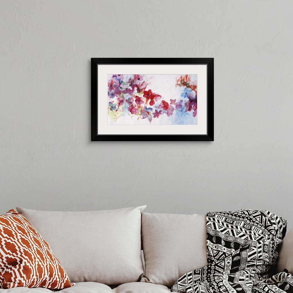 A bohemian room featuring Large horizontal artwork of colorful flowers of red, pink and blue fading into the white background.