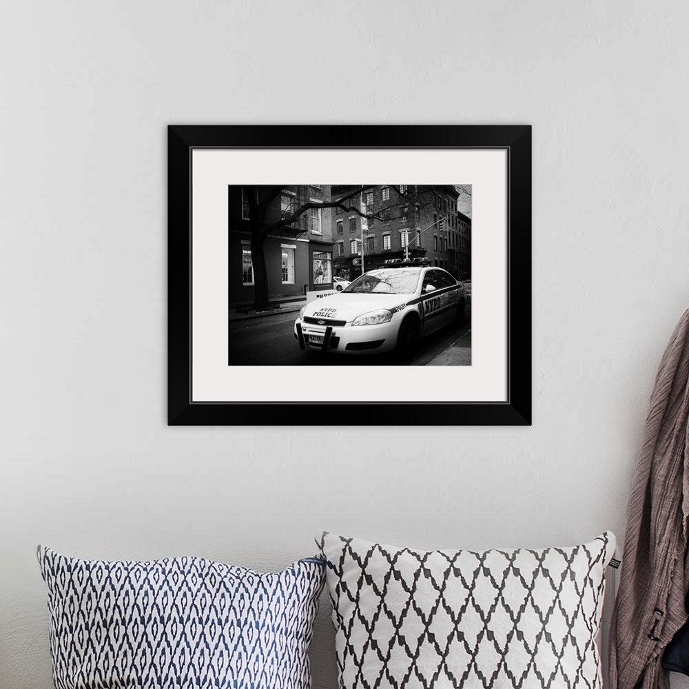 A bohemian room featuring A black and white photograph of an NYPD police car in New York city.
