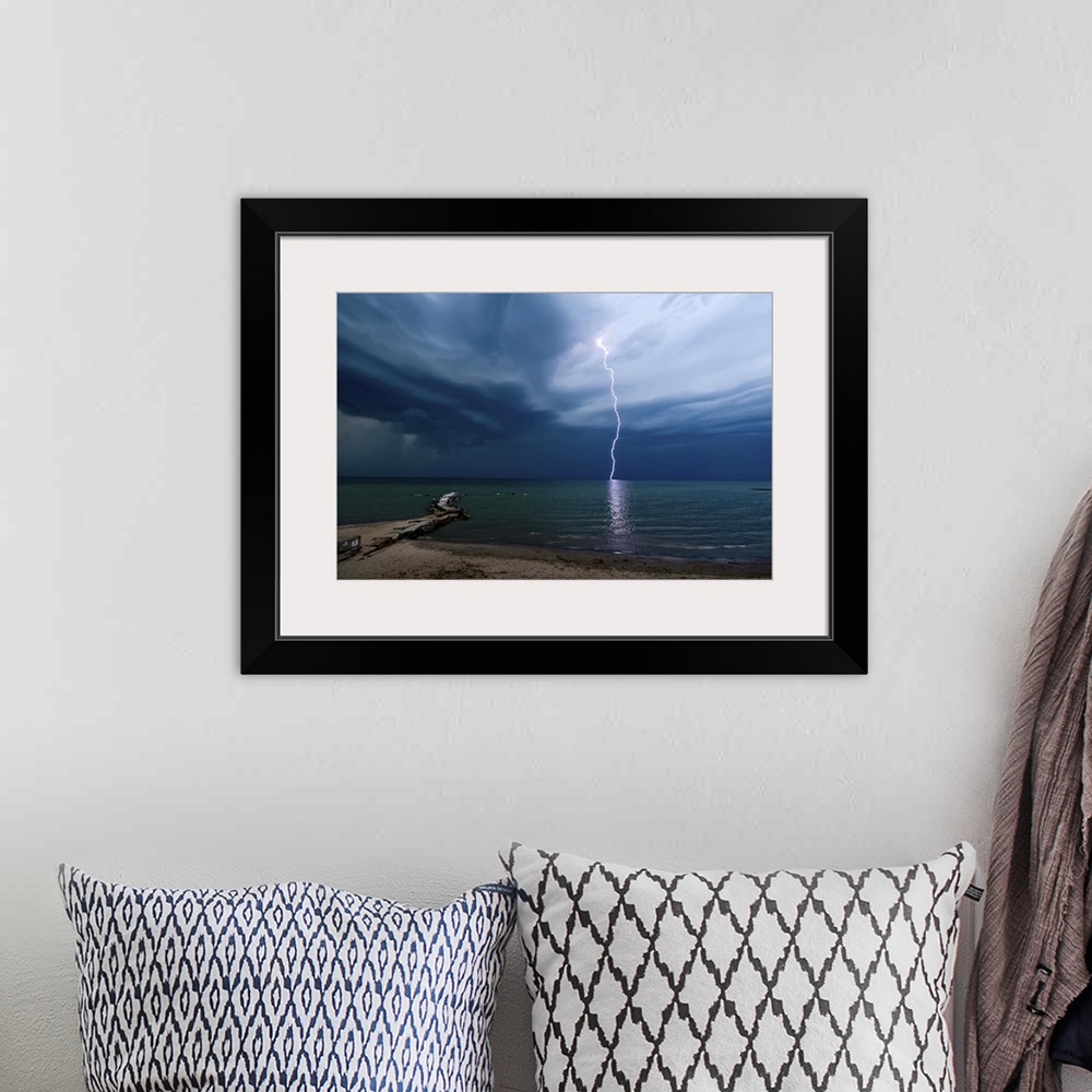 A bohemian room featuring Photograph of a lightning strike over water.