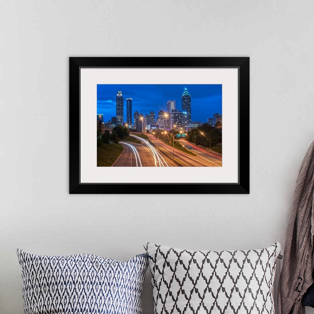 A bohemian room featuring Bright light trails from traffic on the freeway, headed towards the Atlanta, Georgia skyline at t...