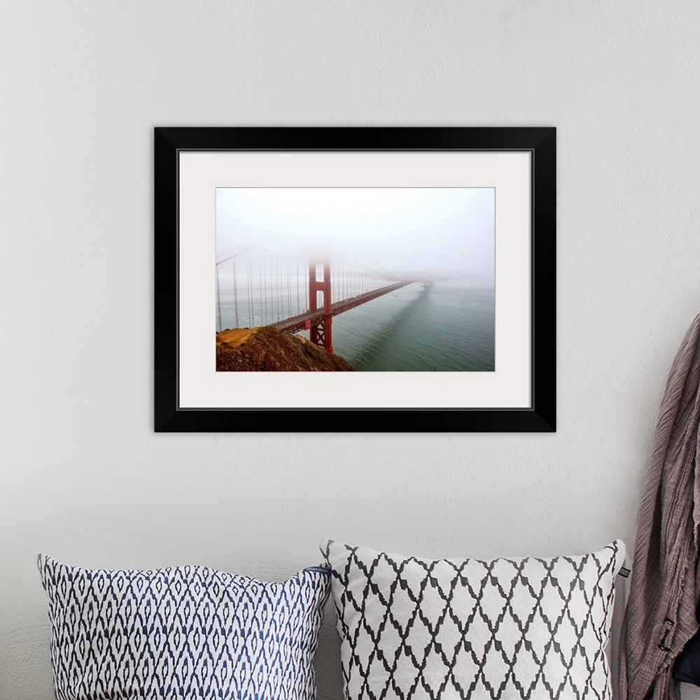 A bohemian room featuring Landscape photograph of fog taking over the Golden Gate Bridge.