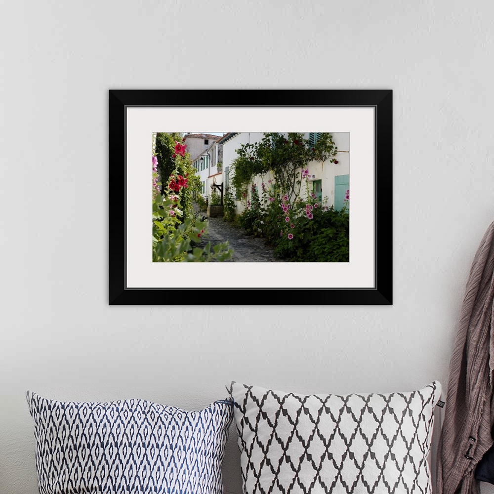 A bohemian room featuring Hollyhocks lining a street with a well, La Flotte, Ile de Re, Charente-Maritime, France